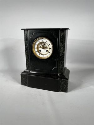 une horloge noire posée sur une surface blanche