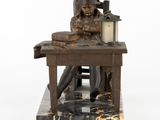 statue of a woman sitting at a desk with a book and a lamp