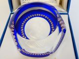 un bol en verre bleu posé dans une boîte sur une table