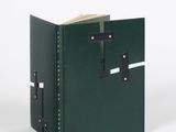 livre en cuir vert avec des fermoirs métalliques sur fond blanc