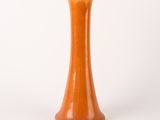 an orange vase that is sitting on a white surface