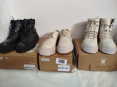 Plusieurs paires de chaussures sont alignées sur des cartons posés sur un lit.