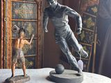 a statue of a man kicking a soccer ball next to a statue of a boy