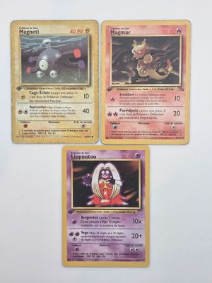 Trois cartes Pokémon sont posées sur une table avec un fond blanc.