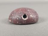 a red stone with a hole in it on a table