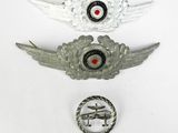 two silver metal badges and a red eye on a white surface