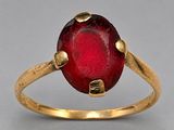 a close up of a gold ring with a red stone on it
