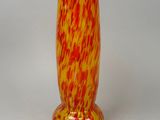 a red and yellow vase sitting on a white surface