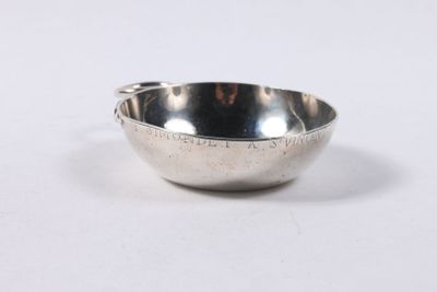 un bol en argent posé sur une surface blanche, avec une cuillère à l'intérieur