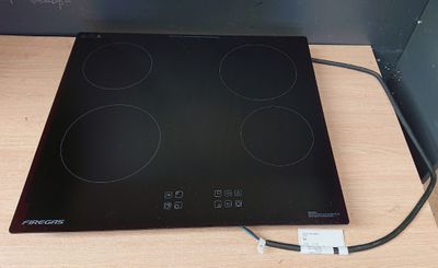 une plaque de cuisson noire à quatre feux, à laquelle est branché un câble