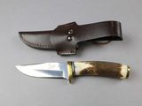 a knife and sheath on the table next to each other