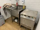 a kitchen with a sink, stove, and trash can in it