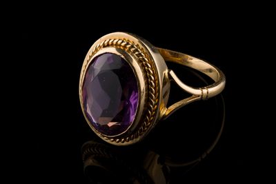gros plan d'une bague en or avec une pierre violette