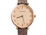 La montre est en or et en cuir marron, avec un motif floral.