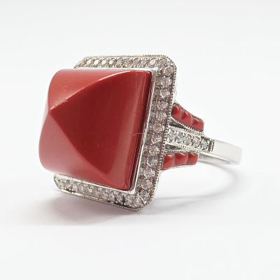 gros plan d'une bague avec une pierre rouge entourée de diamants