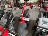Plusieurs tondeuses à gazon sont alignées en rang dans un garage