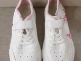 white sneakers with pink trims on them sitting on a couch