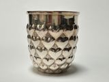 a silver cup with hearts on it on a white surface