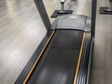 two tread machines in a gym with a monitor on the wall