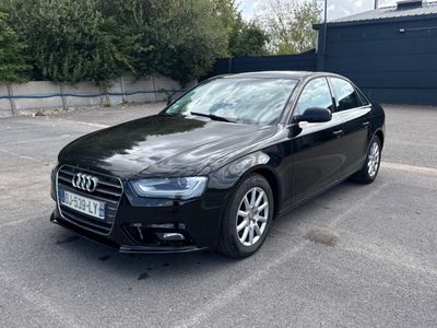 une voiture noire garée dans un parking à côté d'un bâtiment