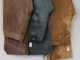 three pairs of pants hanging on a hanger on a wall