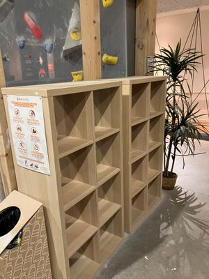a wooden bookcase with a climbing wall in the background