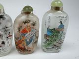 three glass snuff bottles with asian designs on them on a white surface