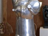 une sculpture métallique représentant une personne tenant une tasse posée sur une table