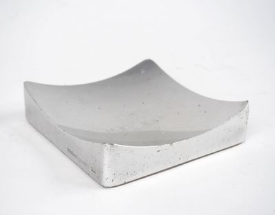 un petit bol en métal posé sur une surface blanche