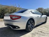 the rear end of a silver sports car parked in a parking lot