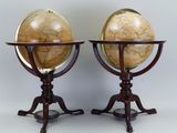 pair of antique globes on tripod stands on a grey background