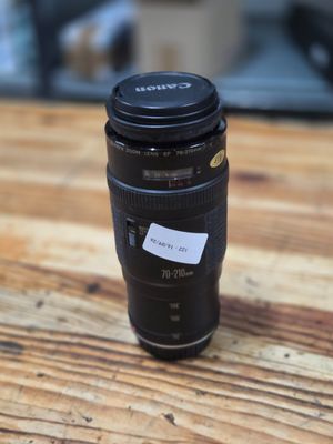 the lens is sitting on a wooden table next to a cup
