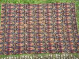 Un vieux tapis est posé par terre, dans l'herbe.