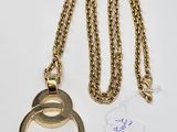 a gold necklace with a ring on it and a tag