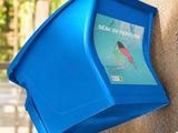 une poubelle bleue accrochée au mur d'un immeuble