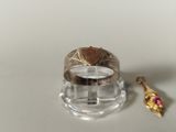 a gold ring with a heart on it next to a pink flower