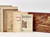 several old books sitting on top of each other on a white surface