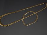 two gold chains and a necklace on a black surface