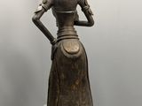 bronze statue of a woman in a dress and hat in a room