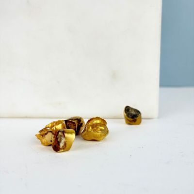 trois pièces d'or sur un fond blanc, à côté d'une boîte blanche