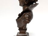 bronze bust of a woman holding a book on a wooden base