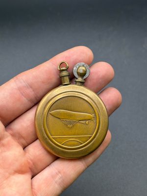 quelqu'un tient une montre de poche en or sur laquelle est représenté un avion