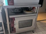 a silver microwave sitting on top of a metal stand