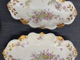 three plates with purple flowers are on a blue table cloth