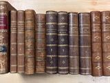 Plusieurs vieux livres sont alignés sur une étagère posée sur un plan de travail en bois.
