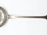 une cuillère en argent avec un manche de cuillère sur une surface blanche