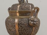 a bronze urn with a dog on top of it