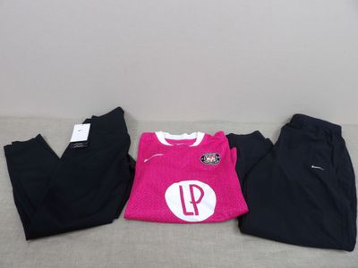 trois paires de vêtements roses et noirs posées sur un canapé