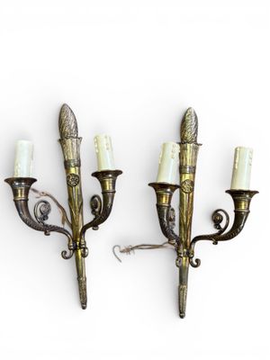 pair of brass wall sconces with white candles on each of them