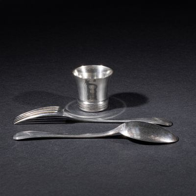 two forks and a silver cup on a black table